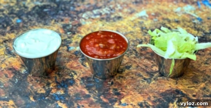 Small bowls containing sour cream, vibrant salsa, and fresh shredded lettuce, perfect condiments for quesadillas