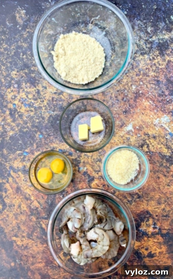 A visual display of ingredients for making keto low carb breaded shrimp, including fresh shrimp, almond flour, parmesan cheese, and eggs