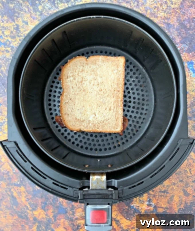 Crispy Air Fryer Grilled Cheese 4 A golden-brown grilled cheese sandwich cooking in an air fryer basket
