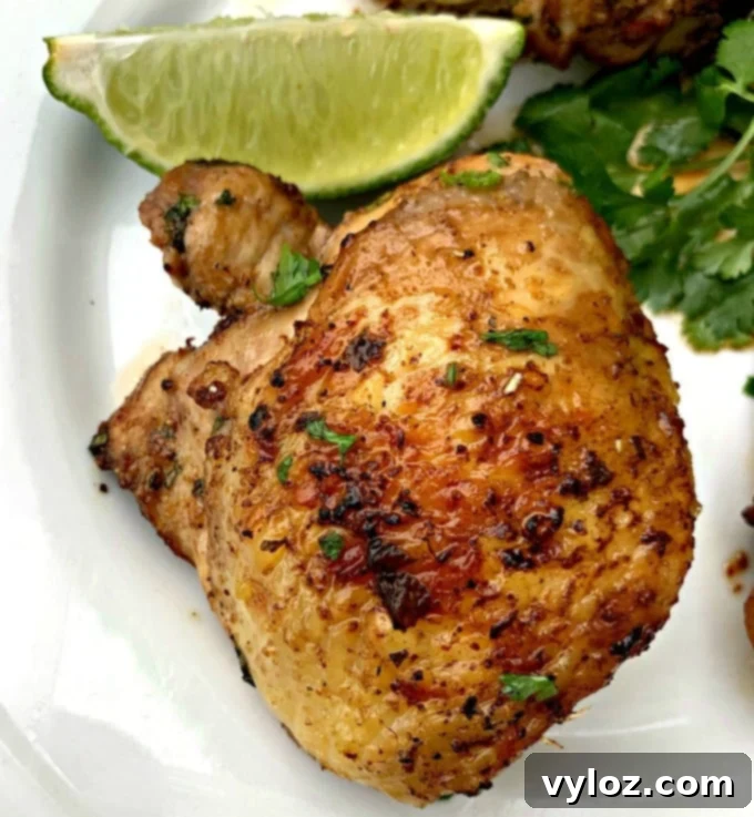 Air fryer keto low carb cilantro lime chicken thighs on a white plate with lime and fresh cilantro, another great Butcher Box recipe.