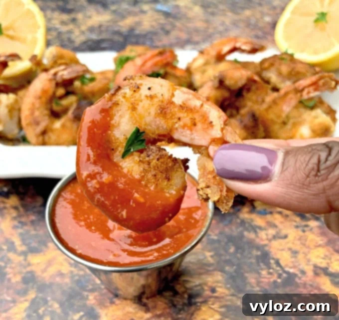 Sugar-Free Homemade Keto Cocktail Sauce 8 person holding keto low carb breaded shrimp dipped in cocktail sauce