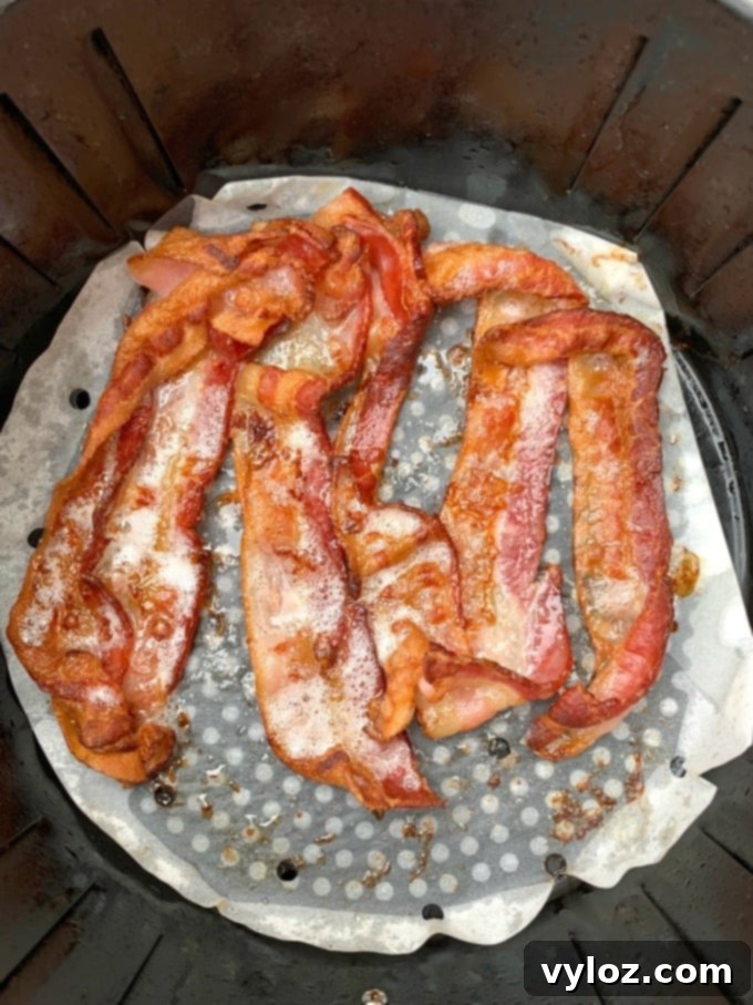 Another perspective of perfectly cooked air fryer bacon on parchment paper.
