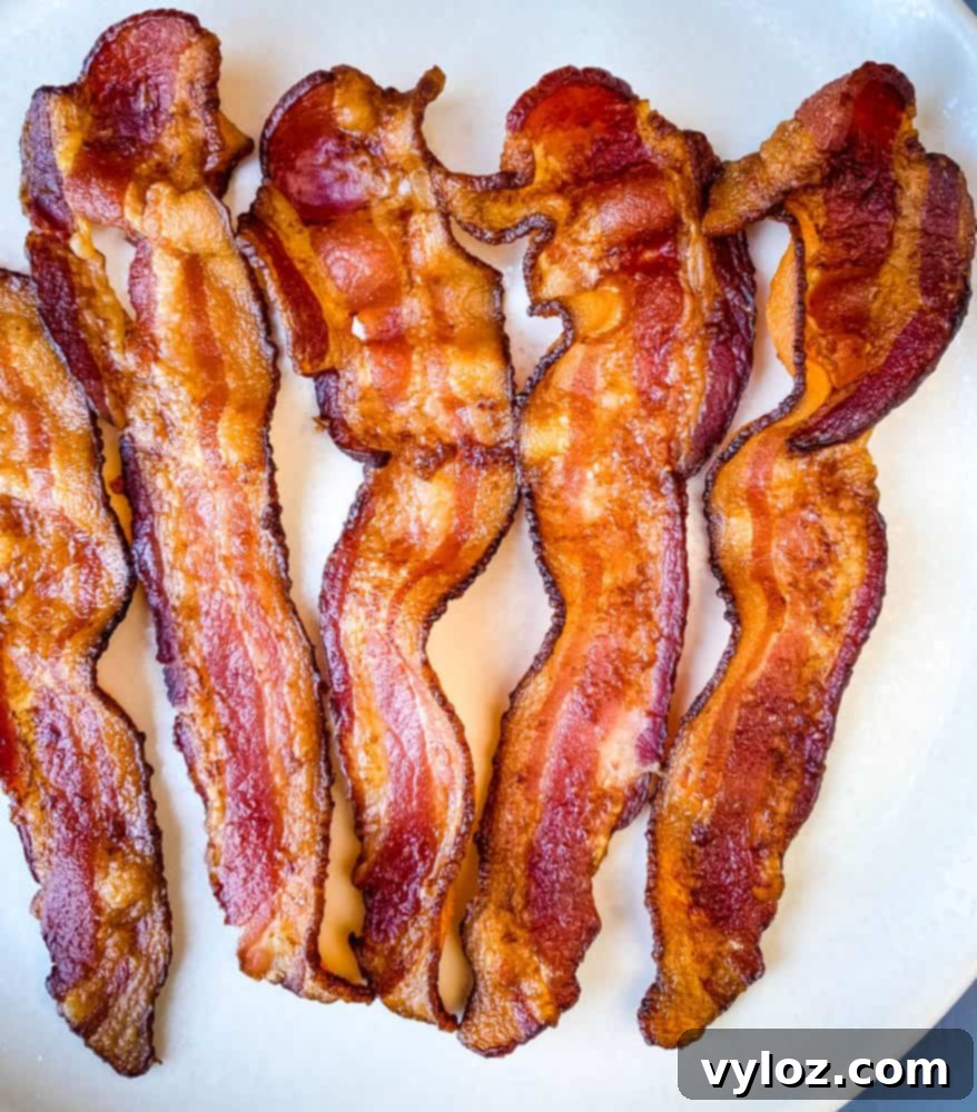 Crispy air fryer bacon displayed on a simple white plate.