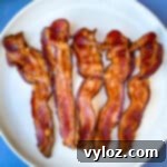 Cooked air fryer bacon on a white plate, ready for serving.