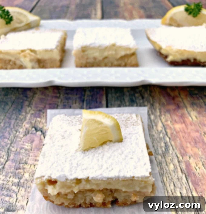 Simple Zesty Keto Lemon Bars 9 Keto lemon bar on parchment paper that has been bitten with two lemons