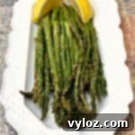 Air-fried roasted asparagus on a white plate with lemon slices