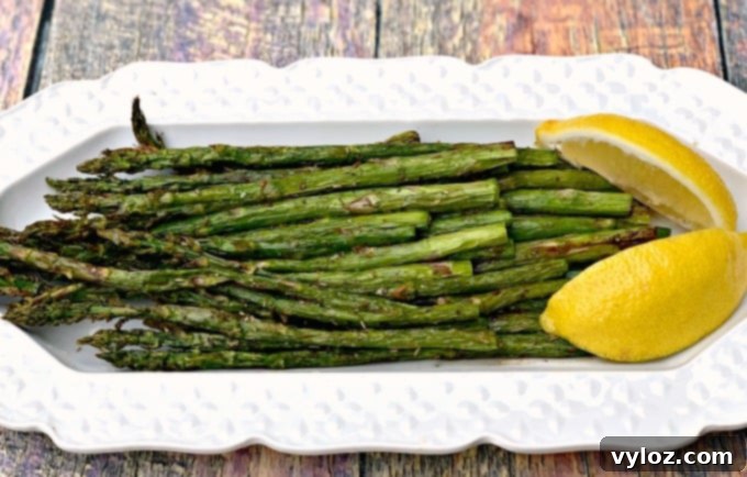 Close-up of air-fried roasted asparagus on a white plate, showcasing its texture