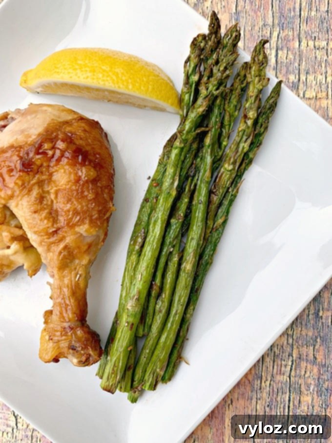 Air-fried roasted asparagus with grilled chicken and lemon on a white plate