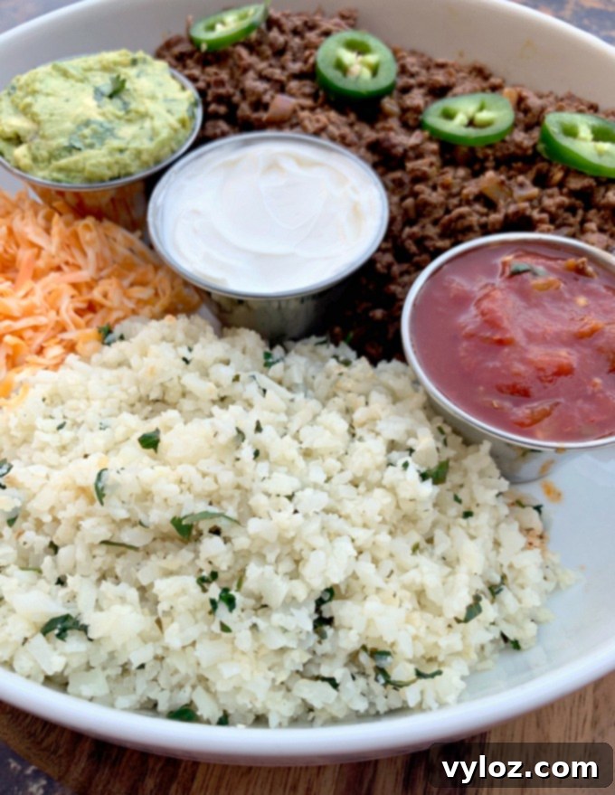 cilantro lime cauliflower rice in a white bowl with salsa, sour cream, and guacamole