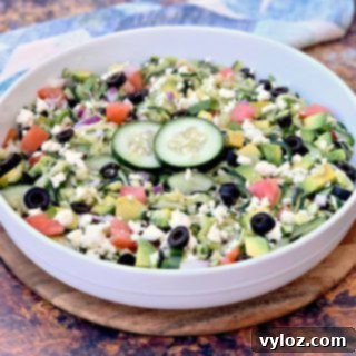 Keto Zucchini Noodle Pasta Salad in a white bowl with colorful tomatoes, olives, cucumbers, feta cheese, and red onions.