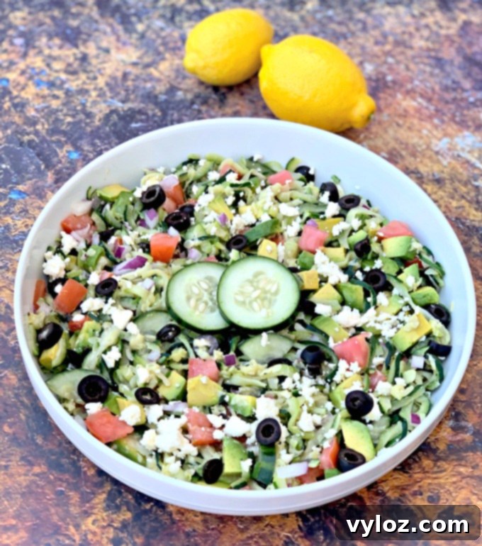 A beautifully presented Zucchini Noodle Pasta Salad with vibrant tomatoes, olives, cucumbers, feta cheese, and red onions, ready to be served.