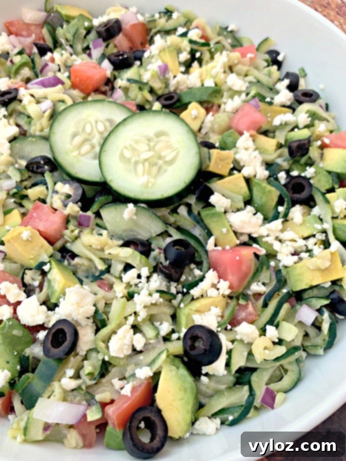 A close-up of a rustic fork gently scooping up a portion of the colorful and fresh Zucchini Noodle Pasta Salad.