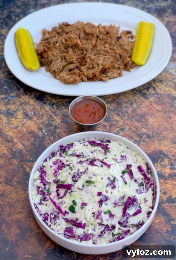 keto low carb coleslaw in a white bowl alongside pulled pork and pickles