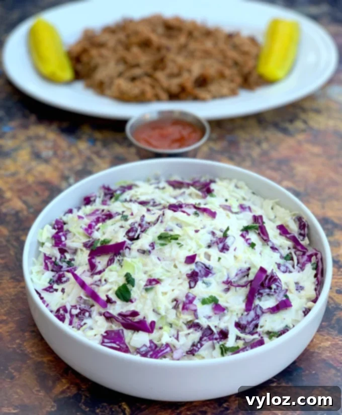 keto low carb coleslaw in a white bowl alongside pulled pork and pickles