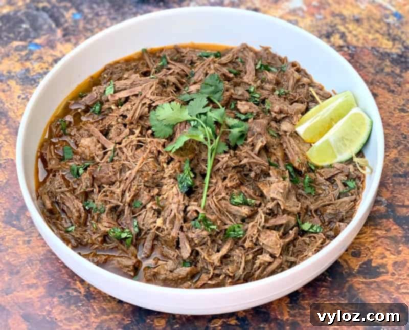 Instant Pot Chipotle Barbacoa Beef 2 Instant Pot keto low carb barbacoa beef in a white bowl, garnished with fresh cilantro and a lime wedge