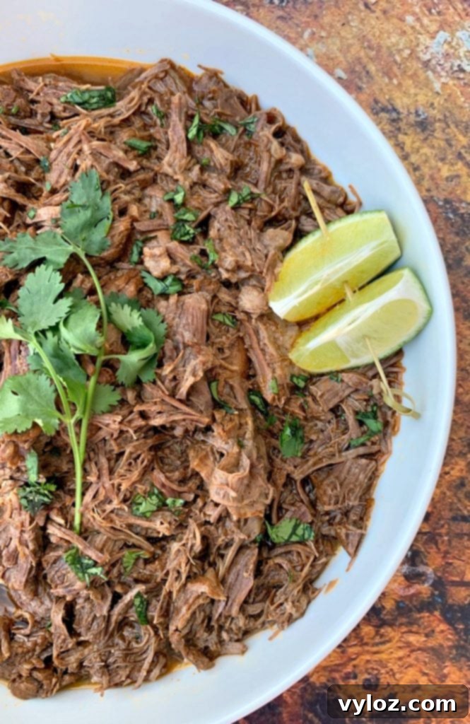 Instant Pot Chipotle Barbacoa Beef 10 Instant Pot keto low carb barbacoa beef with cilantro and limes in a white bowl, ready to be served