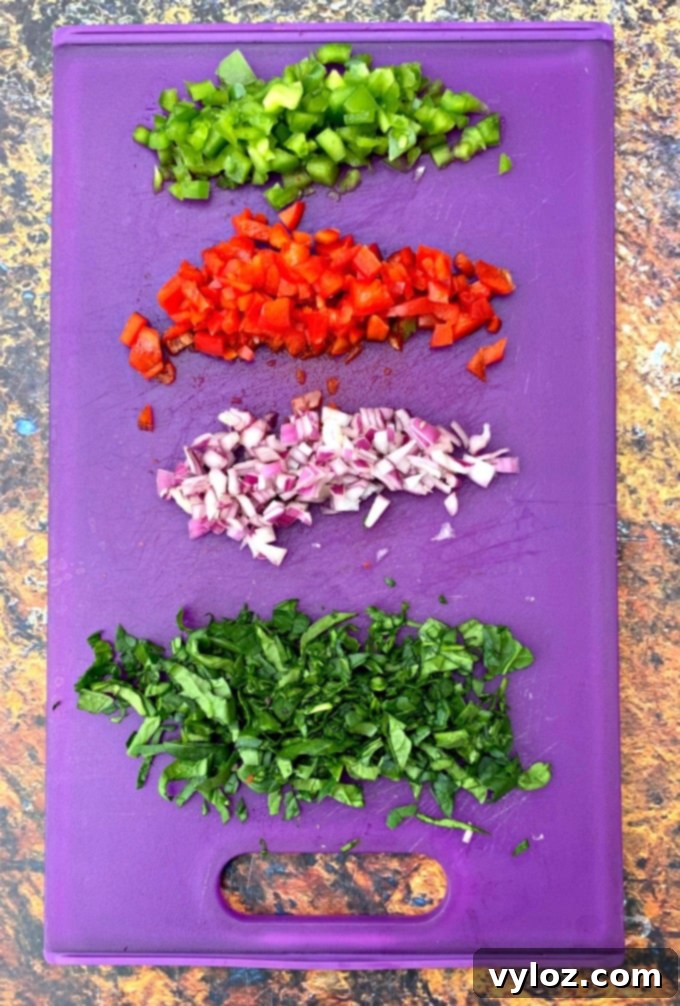 Freshly chopped spinach, colorful bell peppers (red and green), and diced onion ready for a breakfast recipe, arranged on a vibrant purple cutting board.
