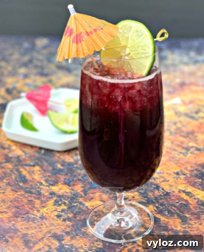 A single glass of keto low carb red wine sangria, garnished with a fresh lime wedge, highlights the drink's rich color and inviting appeal.