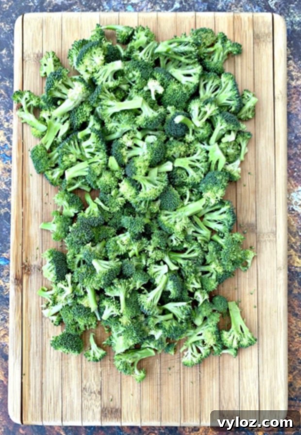 Raw chopped broccoli on a cutting board, ready for the salad