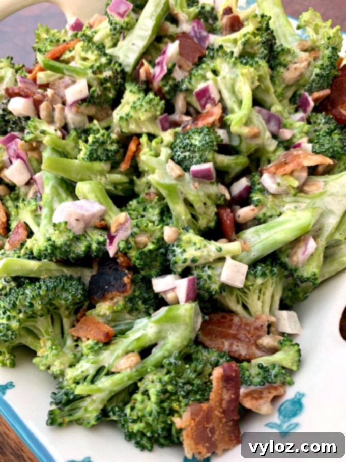 Prepared Keto Low-Carb Broccoli Salad with Bacon, red onions, sunflower seeds, and creamy dressing in a serving bowl