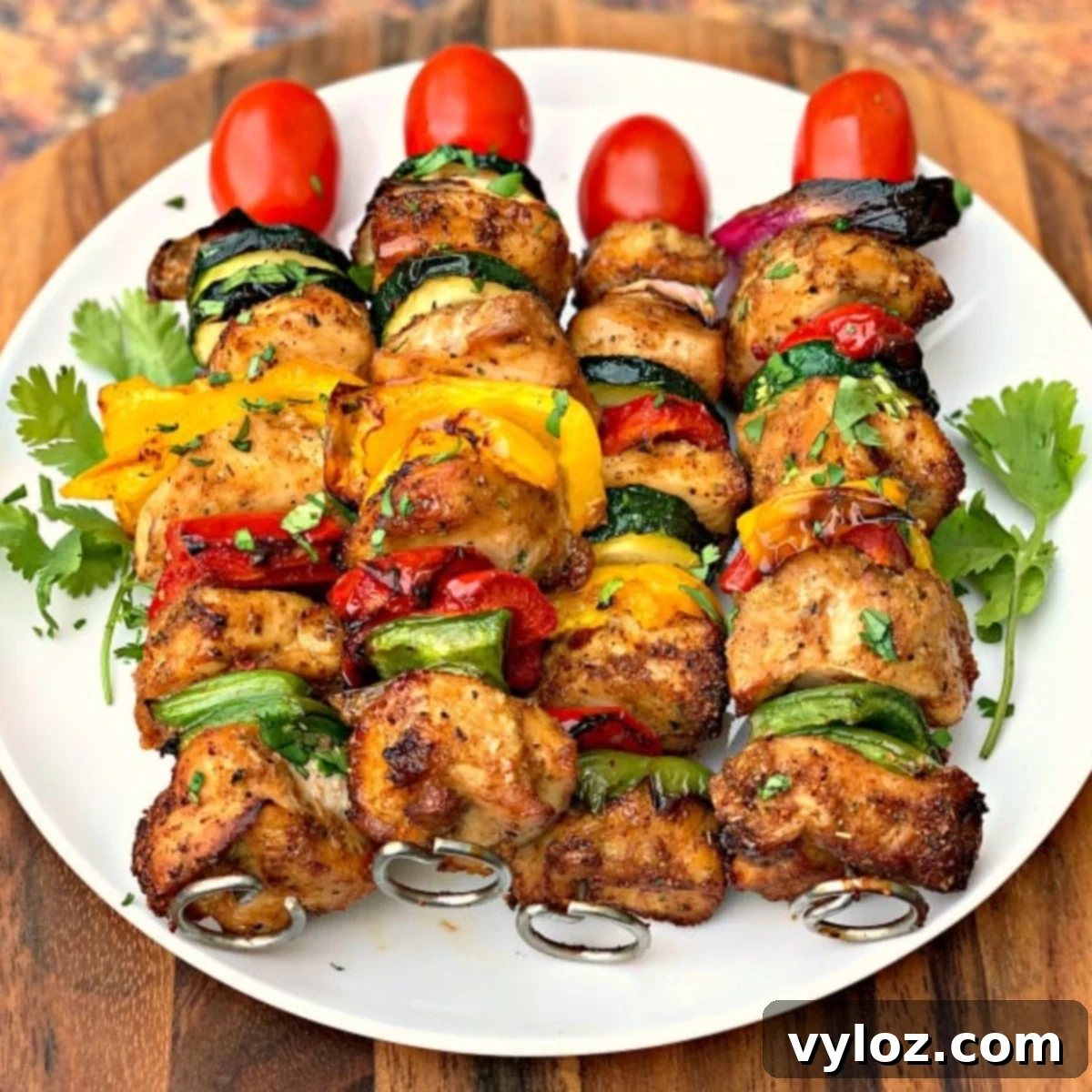 Plate of perfectly cooked Air Fryer Chicken Kebabs with charred edges and vibrant vegetables.