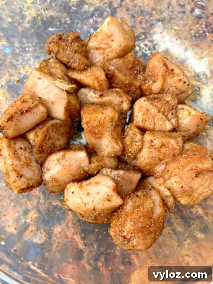 Close-up of seasoned raw chicken in a glass bowl, coated with soy sauce and spices.