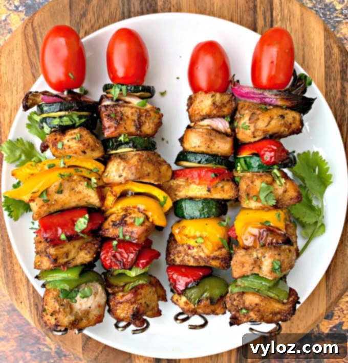 Close-up of a single air fryer chicken kebab on a white plate, highlighting the cooked chicken and vegetables.
