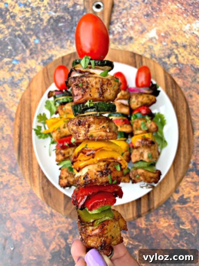 Person holding a perfectly cooked air fryer chicken kebab with a skewer.