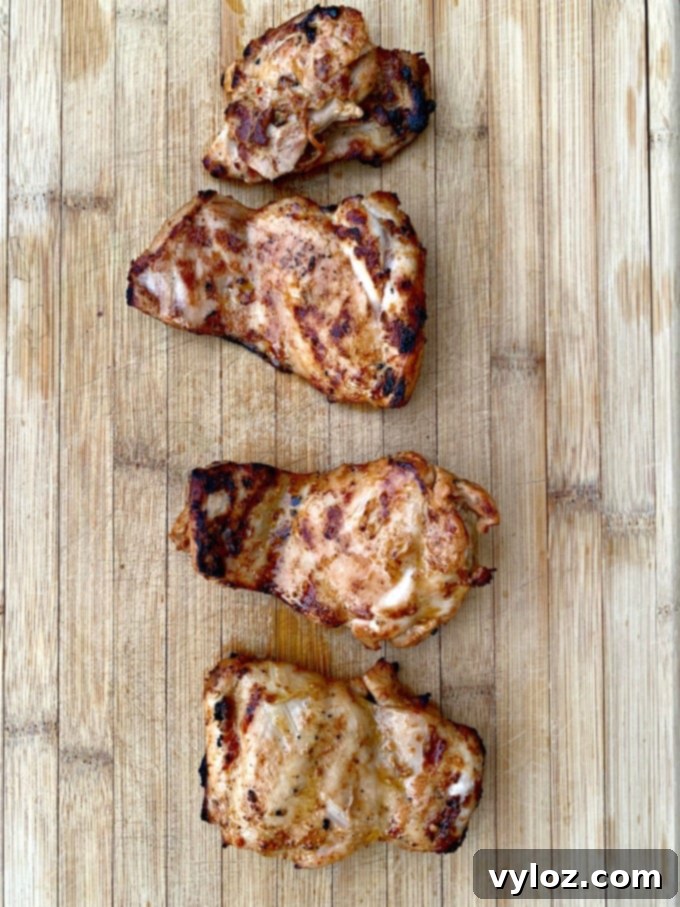 Close-up of perfectly grilled chicken thighs resting on a cutting board, ready to be sliced