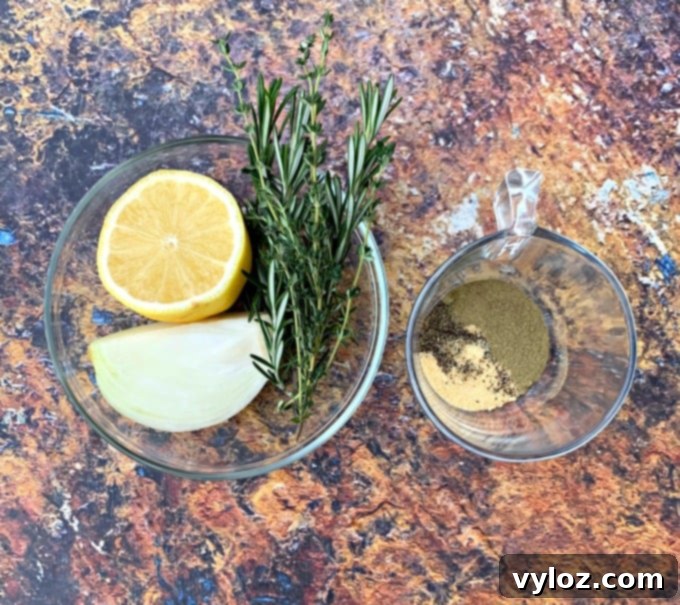 Effortlessly Crispy Air Fryer Whole Chicken 3 fresh lemon, onion, rosemary, and thyme in a glass bowl with seasonings for whole chicken