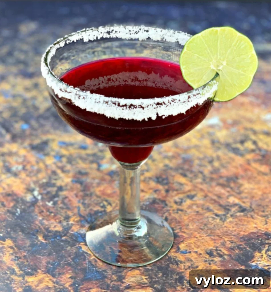 beet margarita in a glass with a sliced lime 