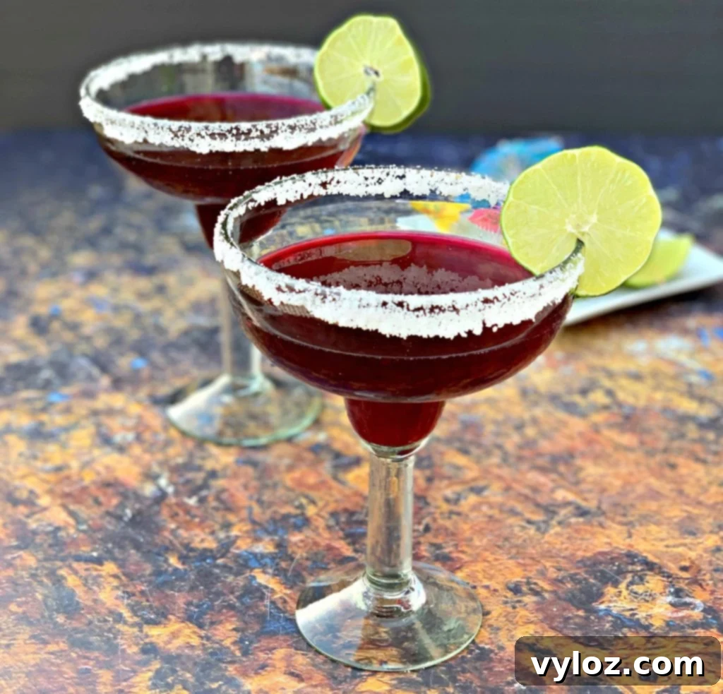 2 beet margaritas in a glass with sliced lime