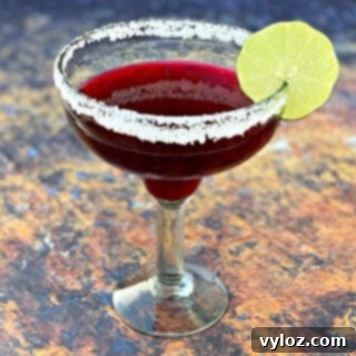 beet margarita in a glass with a sliced lime