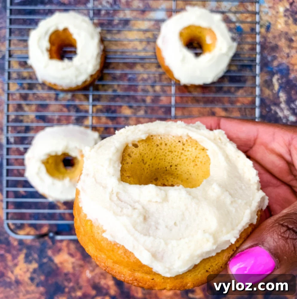 person holding two beautifully frosted keto low carb donuts