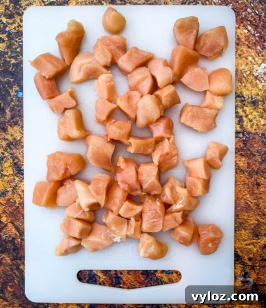 Easy Keto Chicken Broccoli Cheese Bake 4 raw chicken sliced into cubes on a cutting board