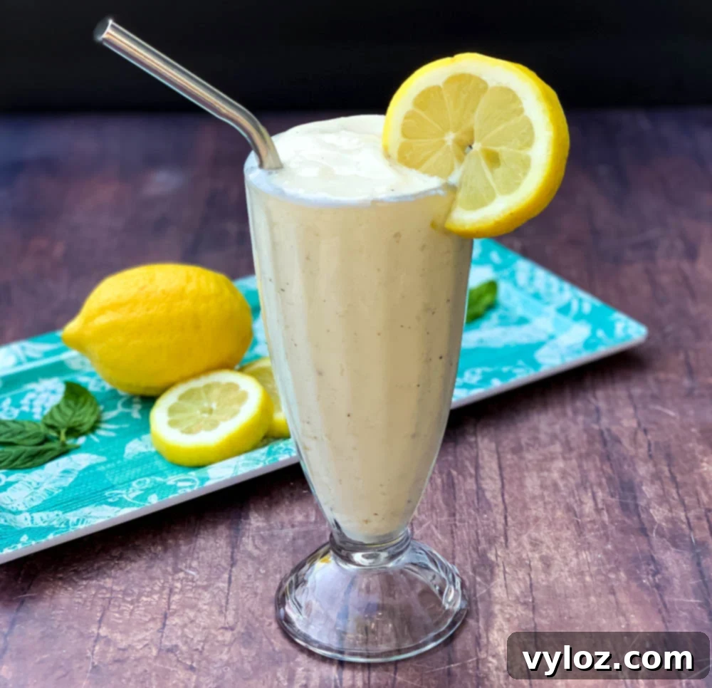 A refreshing glass of homemade Chick-fil-A Frosted Lemonade garnished with a lemon slice and a straw, set against a bright background.