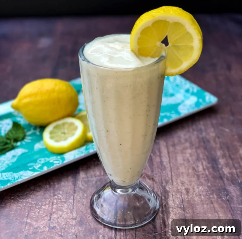 A beautifully presented glass of homemade Chick-fil-A Frosted Lemonade, garnished with a vibrant lemon wedge and a straw, ready to be enjoyed.
