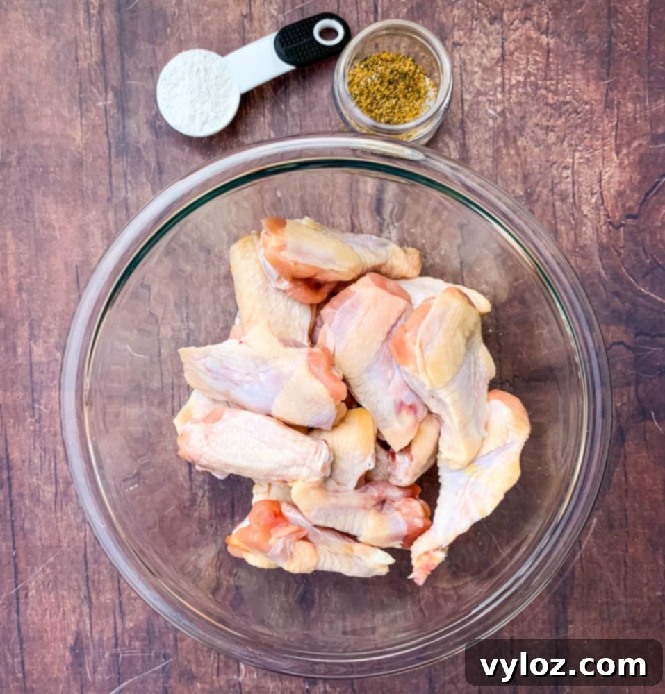 Raw chicken wings seasoned and ready for the air fryer in a glass bowl