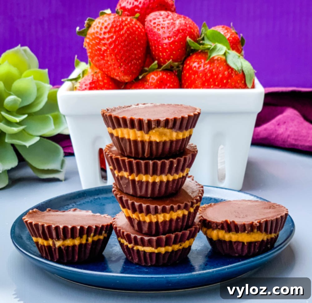A close-up shot of several sugar-free peanut butter cups on a blue plate, with fresh strawberries in the background.