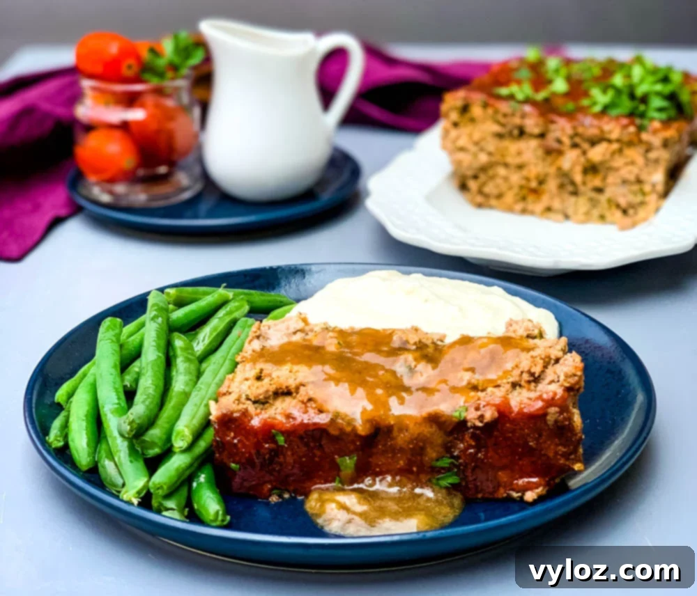 Rich Keto Gravy 6 sliced keto low carb meatloaf on a blue plate with mashed cauliflower and blanched green beans