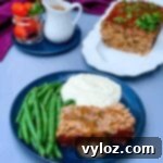 Rich Keto Gravy 7 sliced keto low carb meatloaf on a blue plate with mashed cauliflower and blanched green beans