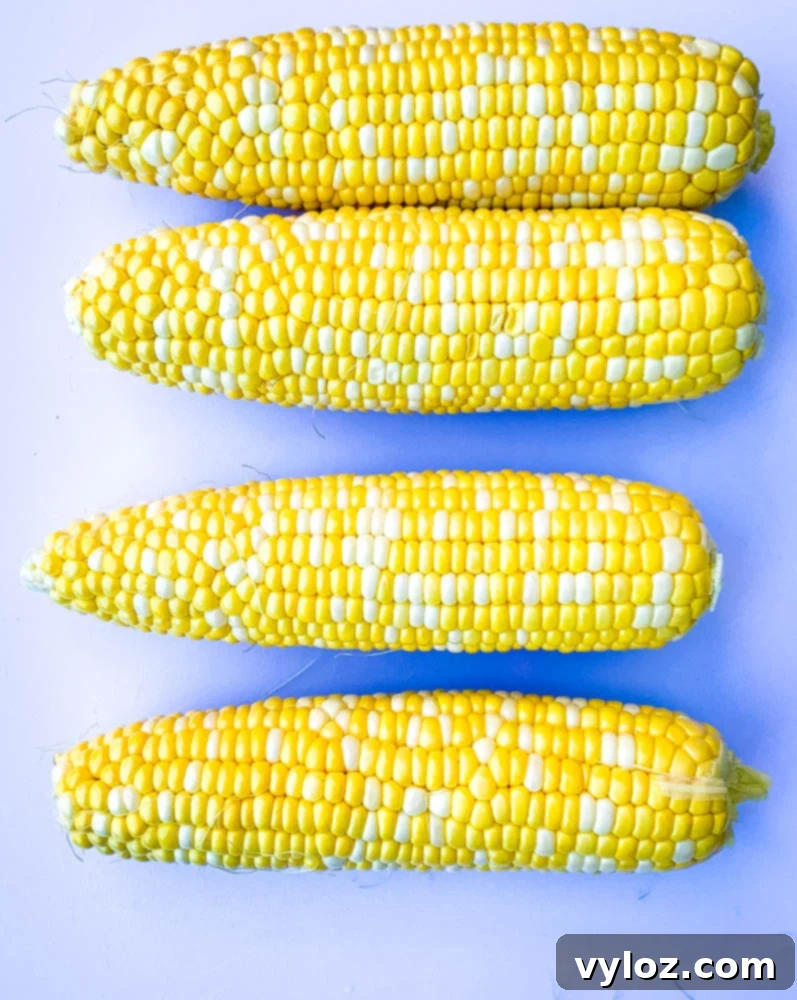 raw shucked corn on the cob on a cutting board, ready for cooking.