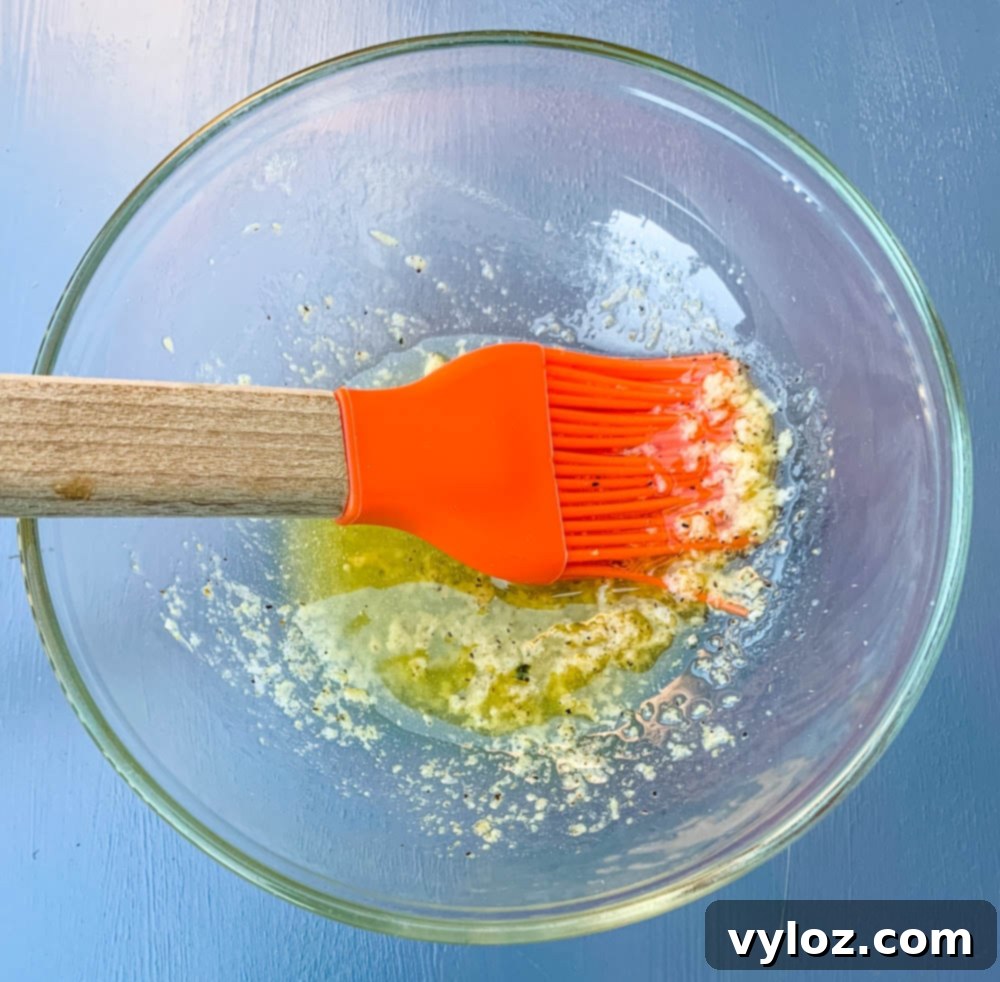 garlic butter sauce in a glass bowl with a cooking brush, perfect for topping corn.