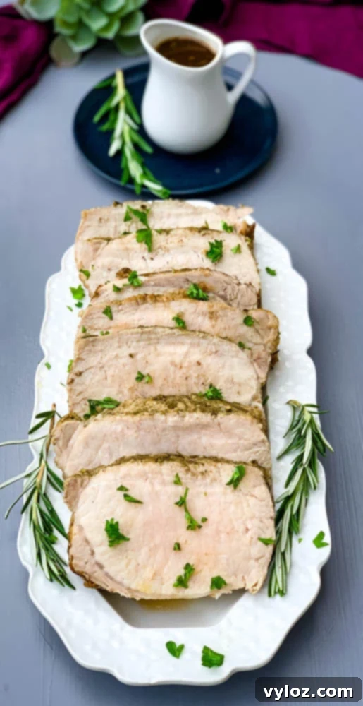 cooked sliced Instant Pot pork loin on a white plate with rosemary