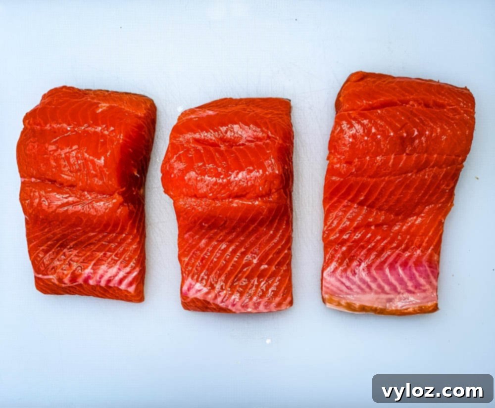 Perfectly Pan-Seared Salmon 4 Raw salmon fillets arranged neatly on a white cutting board, seasoned and ready for cooking