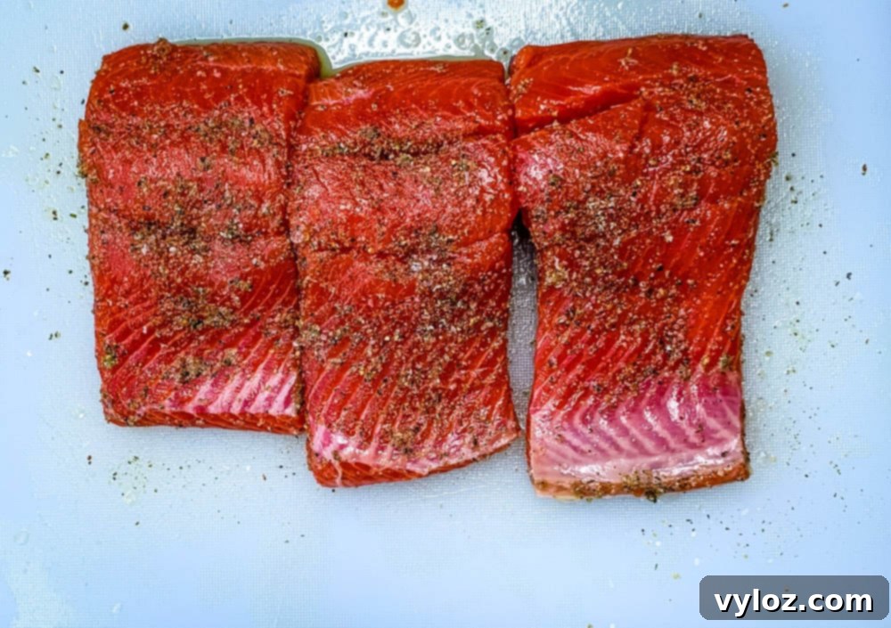 Perfectly Pan-Seared Salmon 5 Raw salmon fillets seasoned with spices on a cutting board, ready for cooking