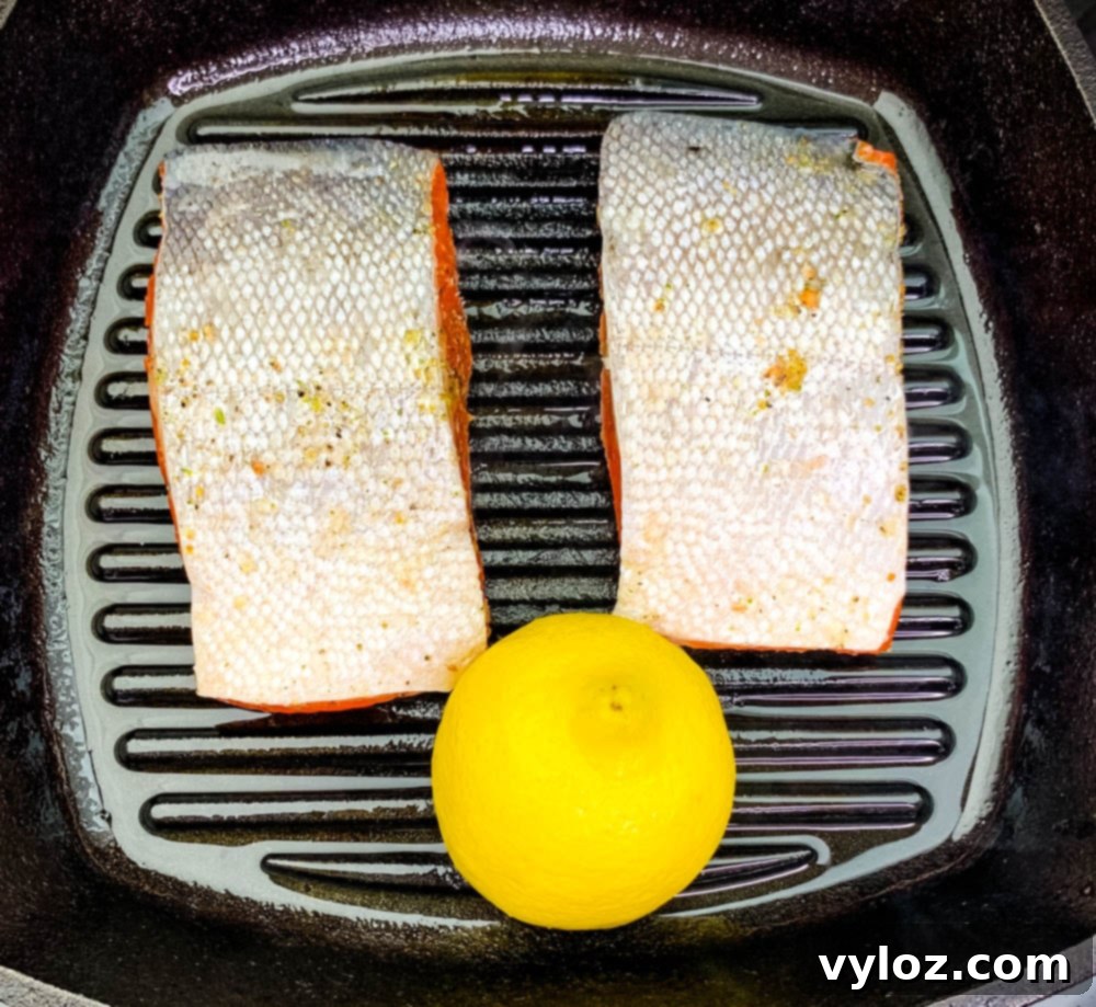 Perfectly Pan-Seared Salmon 6 Pan-seared salmon in a cast iron grill pan with lemon wedges, ready to serve