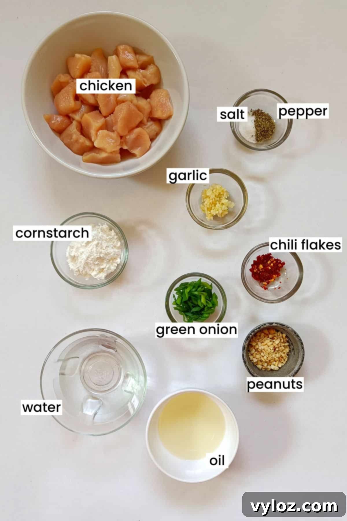 A flat lay image displaying all fresh ingredients laid out on a white background for making honey sriracha chicken.