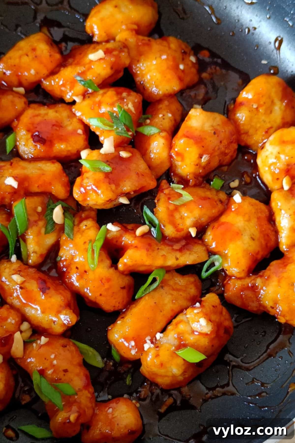 Image showing vibrant, sticky, and juicy sriracha chicken beautifully coated in sauce within a nonstick pan, ready to serve.