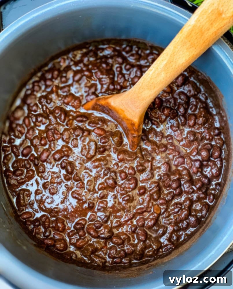 Simple & Savory Instant Pot Black Bean Soup 5 black bean soup in an Instant Pot with a wooden spoon